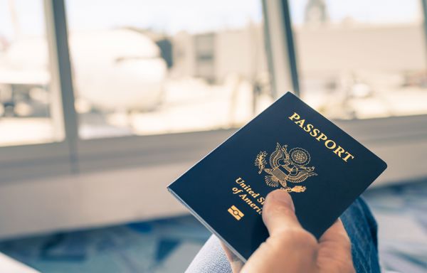A blue US passport with a blurred airport in the background.  ?? ''