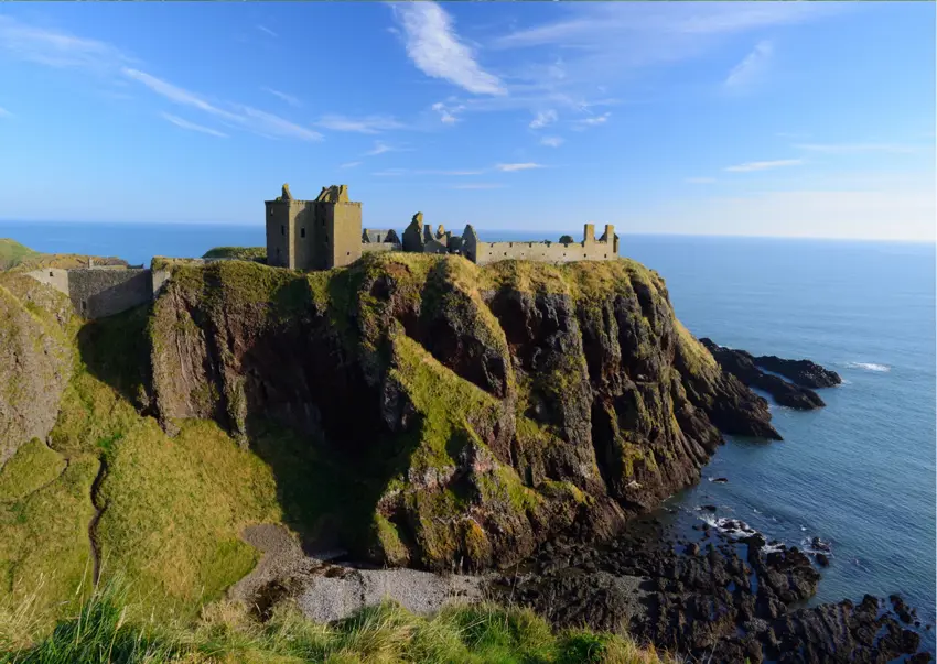 Dunnottar Castle ruins perched dramatically on a sea cliff overlooking the North Sea under a bright blue sky near Stonehaven, Scotland. ?? ''